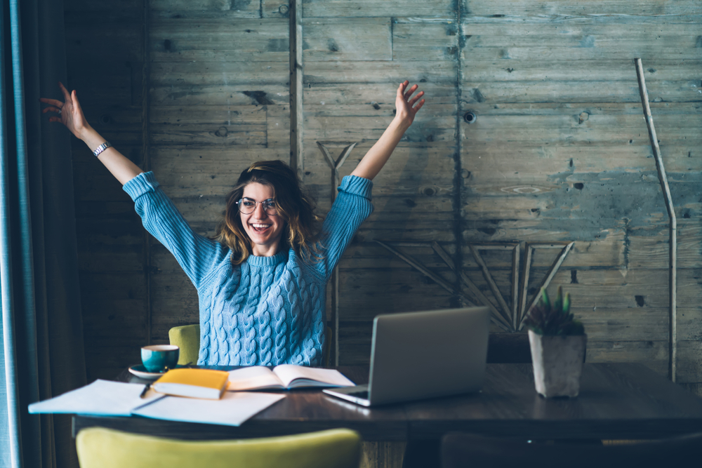 Student,Girl,Sitting,At,Table,With,Open,Notebook,And,Raises